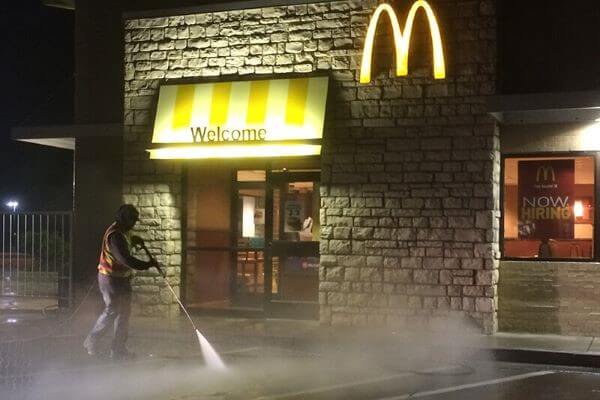 Technician pressure washing the sidewalk areas of a McDonald's restaurant.