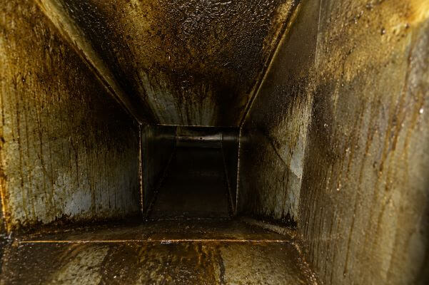 Heavy grease buildup inside a commercial kitchen exhaust duct before professional hood and duct cleaning service by PowerWash Pro